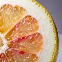 Close-up of fresh pomelo half with juicy segments on grey background and copy space photo