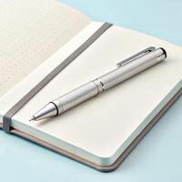 Stylish silver pen resting on open notebook with dotted pages in light blue background with copy space photo
