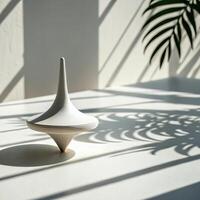 Stylish spinning top sculpture casting shadows on a light surface with a plant in the background for modern decor photo