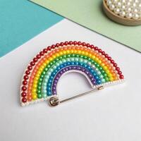 Colorful beaded rainbow brooch on a pastel background with copy space photo