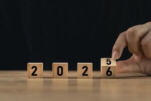 Creative concept of changing the year from 2025 to 2026 using wooden blocks with numbers, symbolizing time transition and new beginnings photo