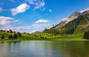 a beautiful mountain lake surrounded by green grass and trees photo