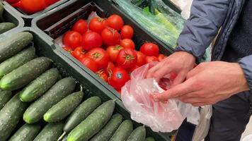 Man choosing cucumbers and tomatoes in vegetable section in supermarket video