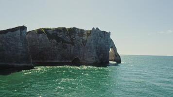 A large rock formation in the ocean with green water photo