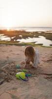 Little child girl playing with sand on ocean beach with sunset tones video