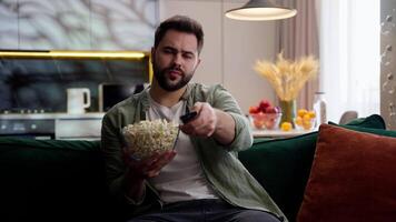 Upset unhappy sad Caucasian man male homeowner guy spectator holding bowl popcorn snack broken controller boring show error resting failed relaxing failure bad channel sitting sofa at home living room video