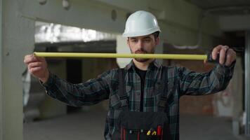 construtor homem arquiteto segurando a medida régua construção medindo fita metro caucasiano cara masculino inspetor capataz reparador faz-tudo indústria engenheiro usando medição ferramenta Tamanho inspecionando construção video