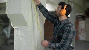 homem construtor arquiteto verificação parede a medida fita régua construção medindo ferramenta cara masculino inspetor capataz reparador faz-tudo industrial engenheiro usando medição instrumento inspecionando construção video