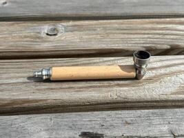 Wooden smoking pipe with metal bowl resting on rustic wooden surface, showcasing craftsmanship and natural materials in a serene setting photo