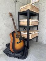 Acoustic guitar resting against a black shelf with woven baskets, showcasing a minimalist interior design and inviting atmosphere for music lovers photo