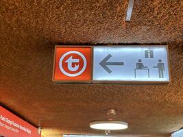 Warsaw, Poland - May 22, 2025, Directional sign indicating left turn towards service point with icons of people and information, showcasing urban navigation in a public transport setting photo
