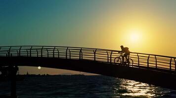Cyclist Silhouette Crossing a Bridge Over the Sea at Sunset video
