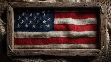 Vintage American flag displayed in a weathered wooden frame on a rustic burlap background photo