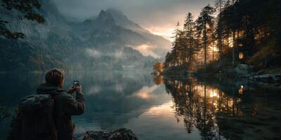 Individual capturing the beauty of a lake at sunrise surrounded by mountains and trees in serene nature setting photo
