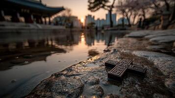 Evening light reflects on water near a cross in a serene garden setting photo