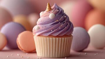 Colorful decorative cupcake topped with purple frosting and sprinkles surrounded by pastel macarons on a pink surface photo