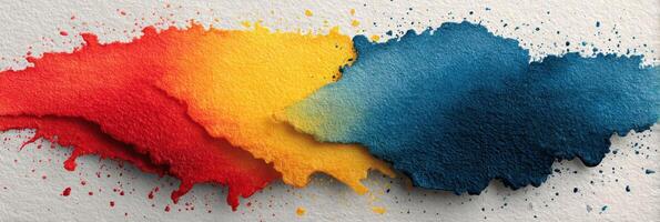 Vibrant splashes of red, yellow, and blue watercolor on textured paper create an artistic display of color blending photo