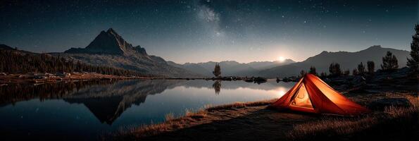 Camping under the stars at a tranquil lake with a vibrant orange tent and mountains in the background photo
