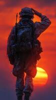 Soldier salutes at sunset with vibrant orange sky illuminating the scene in a moment of reflection and honor photo