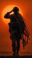 Soldier saluting while draped in flag against a vibrant sunset backdrop at a military memorial site photo