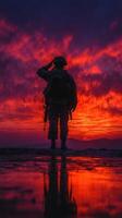 Soldier saluting at sunset with vibrant sky and reflections on the ground in a serene landscape photo