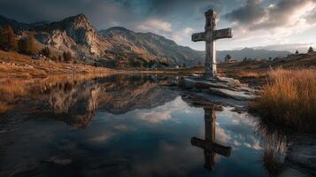 Scenic landscape with a cross by a tranquil lake surrounded by mountains during golden hour photo