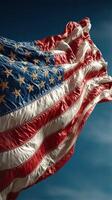 Waves of the American flag under a clear blue sky during midday, symbolizing patriotism and freedom photo