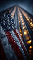 City skyline illuminated at night with a close-up of a wet American flag reflecting the lights photo