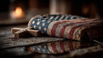 Old American flag resting on a wooden surface with a cross nearby in low light setting photo