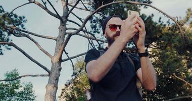A man enjoys nature, taking selfies and photos of a majestic tree video