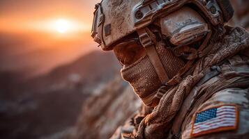 Soldier in tactical gear watches sunset over mountainous terrain in a desert environment during operational deployment photo
