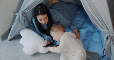 A mother and baby share joyful moments in a cozy teepee video