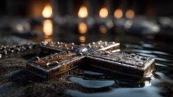 Close-up of a wooden cross resting in water with droplets, illuminated by soft candlelight during a reflective evening moment photo