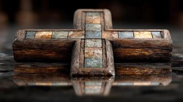 Decorative wooden cross with stone inlays displayed on a dark reflective surface in a serene setting photo