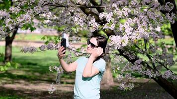 A woman taking a photo of herself in front of a tree video