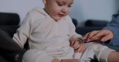 A baby plays with a toy on a couch, giggling and exploring video