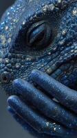Detailed close-up of a lizard showcasing blue scales and a hand adorned with matching glitter in an artistic composition photo