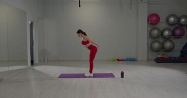 Girl performs back and leg stretch in fitness studio during workout session video