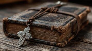 Antique book with silver cross pendant resting on wooden surface in soft light photo