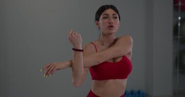 Girl stretches shoulders and triceps in a fitness studio during an afternoon workout session to improve flexibility and strength video