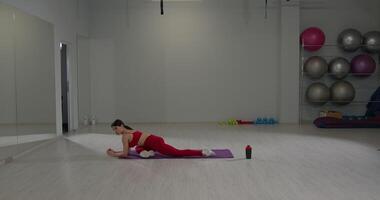 Girl performs back and leg stretches in a fitness studio during a workout session to improve flexibility and strength video