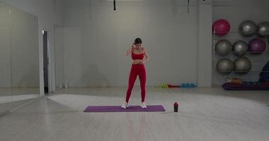 Girl stretches her back and legs in a bright studio setting during a fitness session in the afternoon video