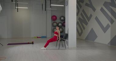 Engaging in reverse chair pushups for triceps development in a modern fitness studio setting video