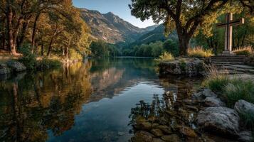 Beautiful river landscape with mountains and cross at sunrise in a serene natural setting photo