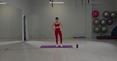 Girl bends to the side while preparing for a workout in a modern gym environment with exercise equipment video
