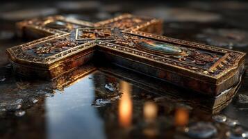 Ornate metallic cross resting on wet stone surface reflecting warm light in a serene indoor setting photo