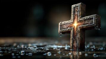 Wooden cross illuminated by a soft glow while resting on wet surface surrounded by droplets at dusk photo