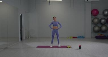 Athletic girl engages in stretching exercises while tilting her head in a modern gym setting video