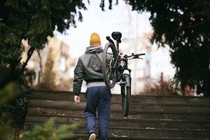 Man Carrying Bicycle Up Steps in Urban Park photo