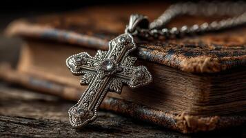 Detailed silver cross pendant resting on an antique leather-bound book in warm light photo